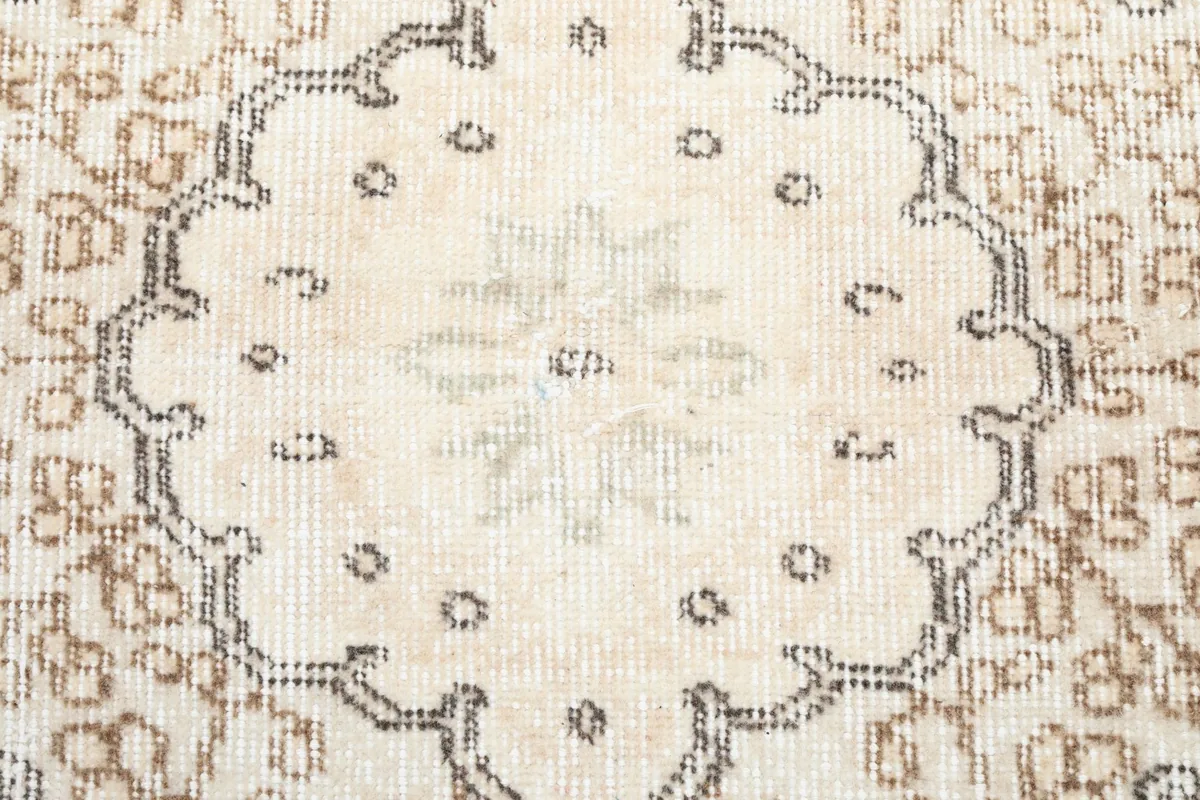 Detailed view of the intricate patterns within the central medallion of the ivory rug