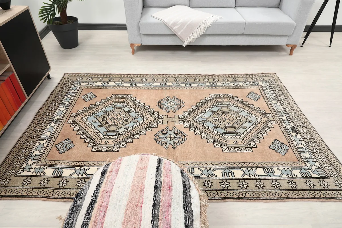 Full room view of the vintage tan and blue rug, demonstrating its presence as a focal point.