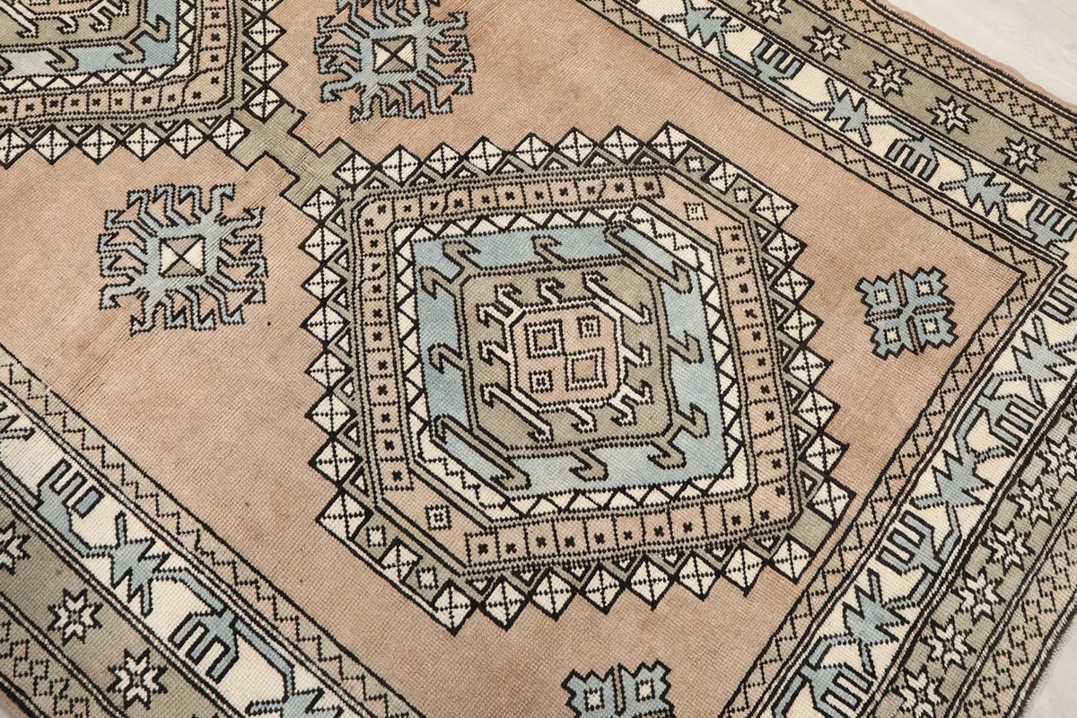 Close-up of the central diamond medallion motif with blue and beige accents on the tan field.