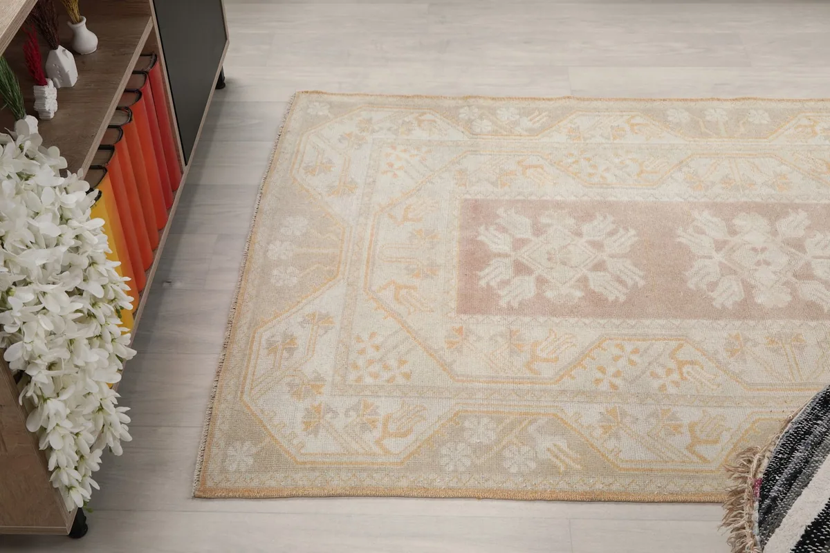 Angled view of the rug, showing the full length of the central rose panel and surrounding beige border