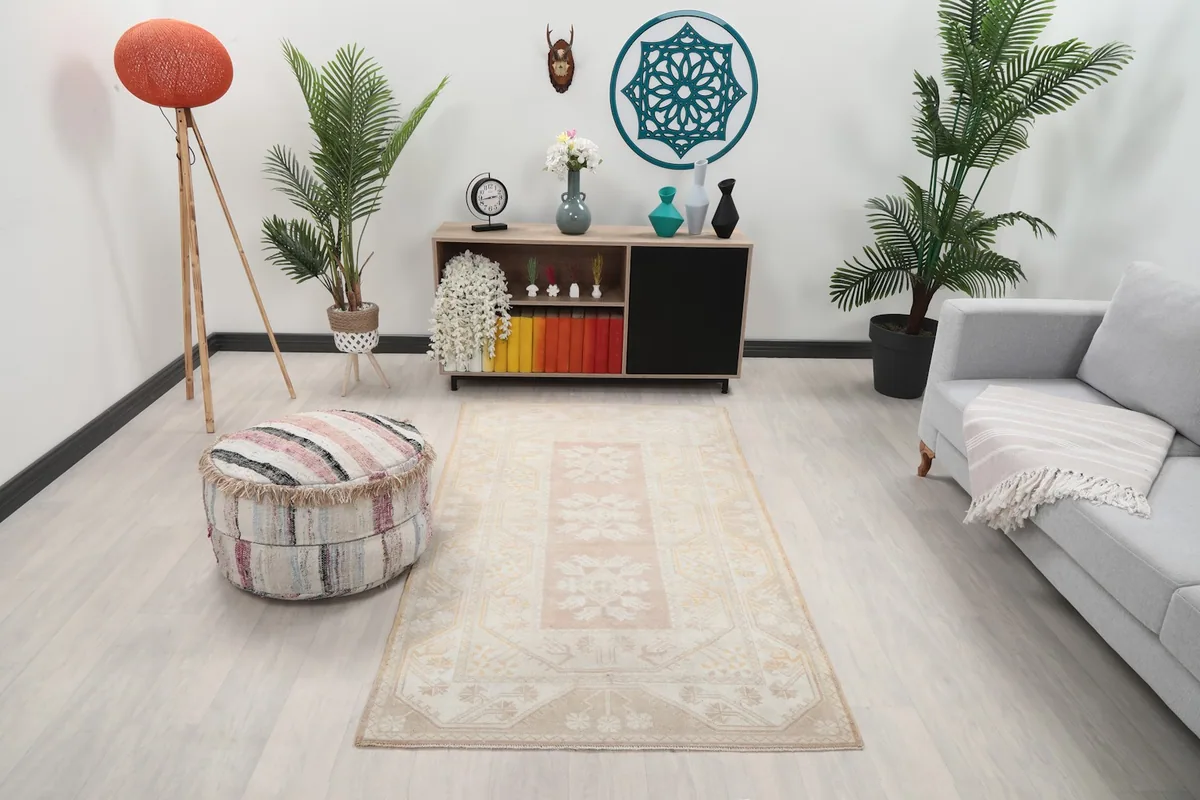 Vintage beige and rose rug styled in a living room setting with a sofa and ottoman