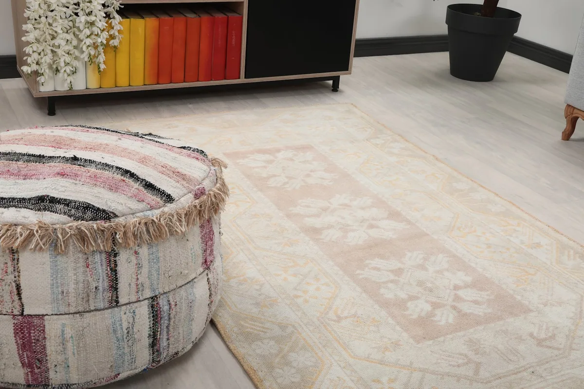 Close-up of the rug's central rose field and beige border next to a striped ottoman