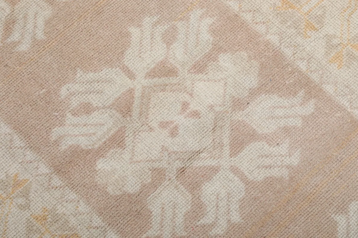 Close-up of a single ivory floral motif against the rose background in the rug's center
