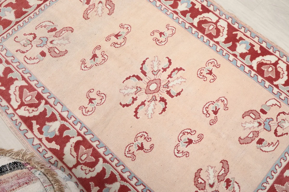 Close-up of the central floral medallion and surrounding motifs on the beige field of the rug.
