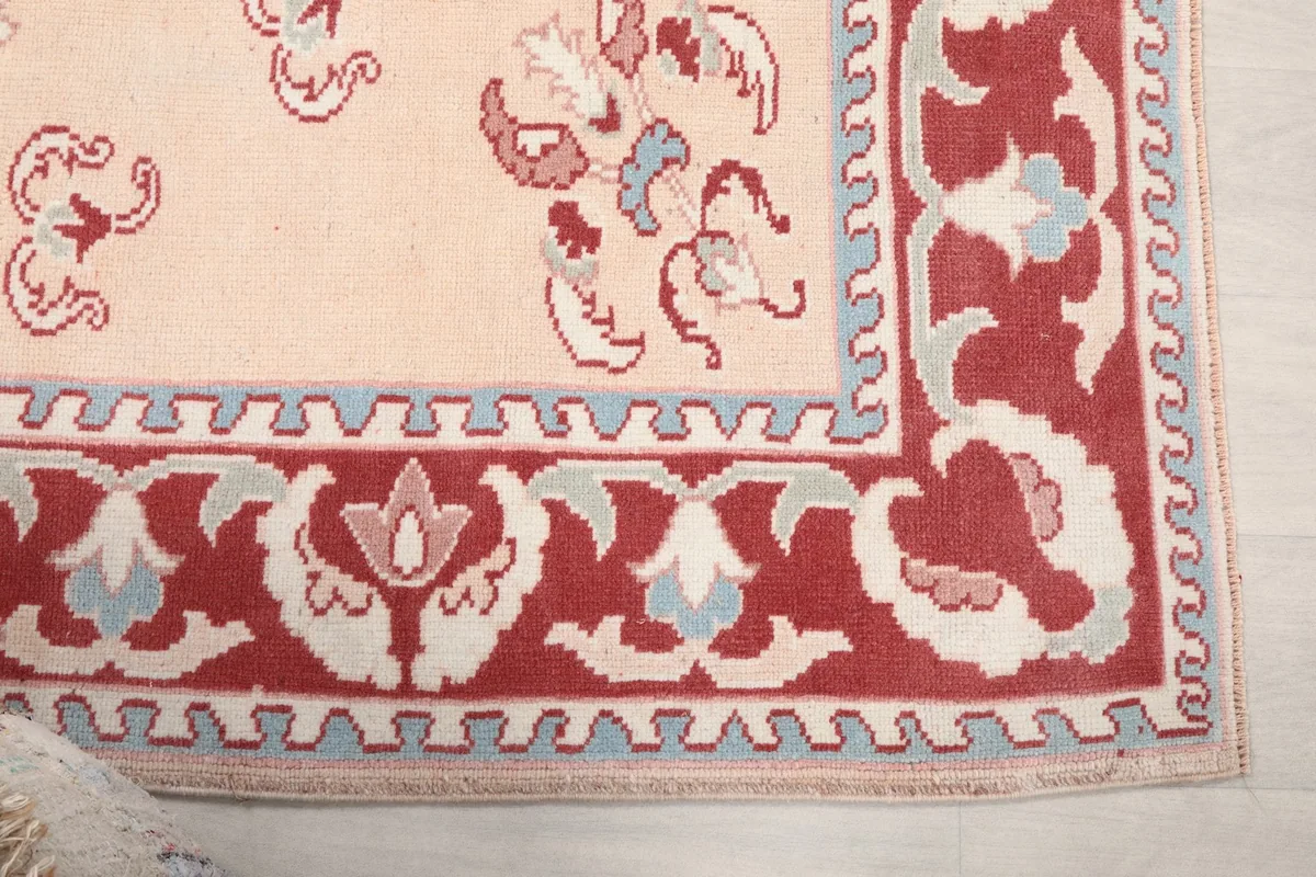 Detail of the red floral border with blue and gray accents, showcasing the hand-knotted wool texture.