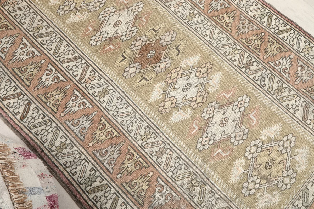 Angled close-up showing the central beige field and patterned border of the rug