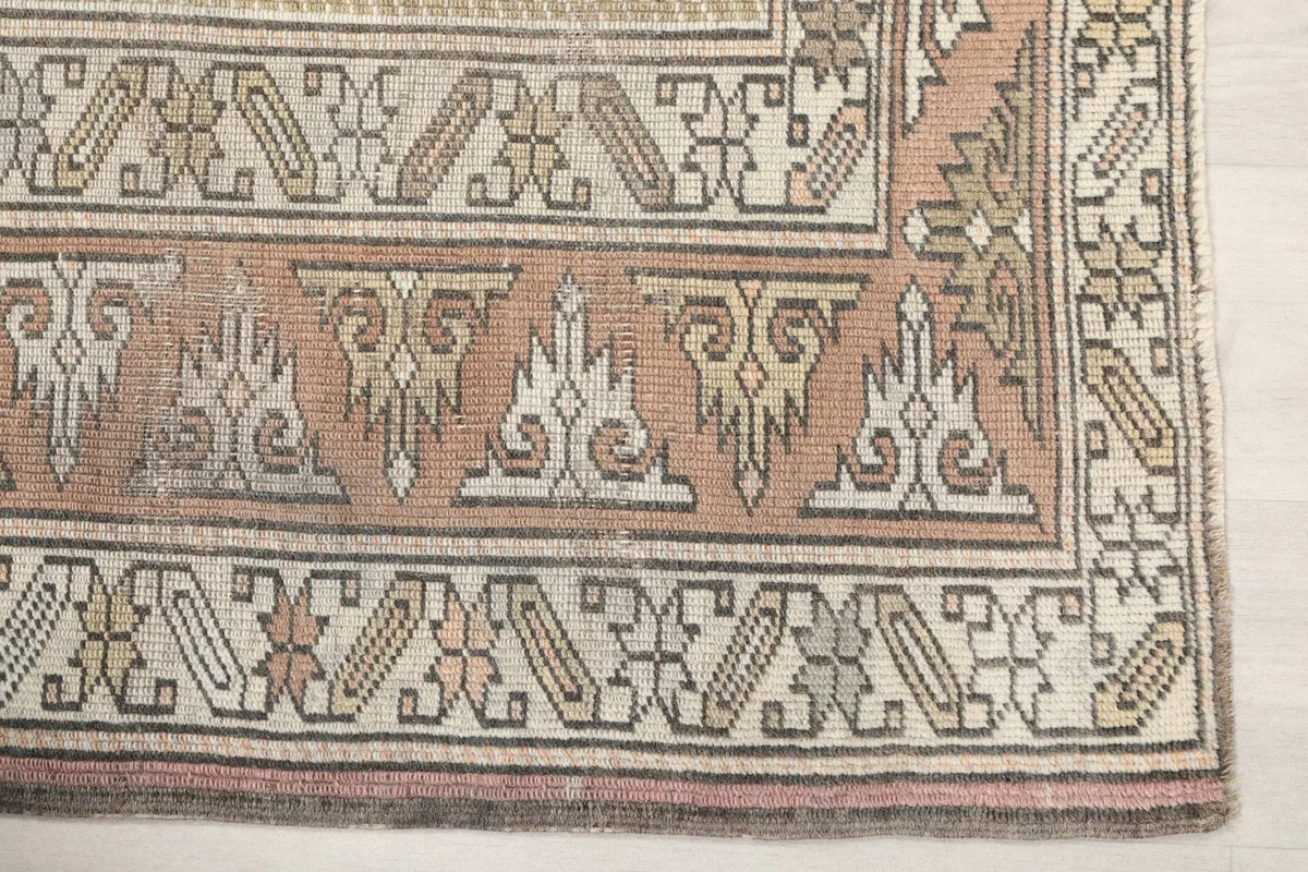 Detail of the rug's rust-colored border with geometric motifs and subtle wear
