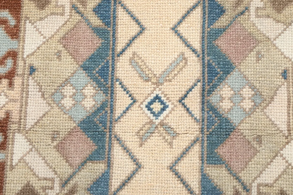Macro detail of the central beige motif and surrounding blue and tan geometric patterns.