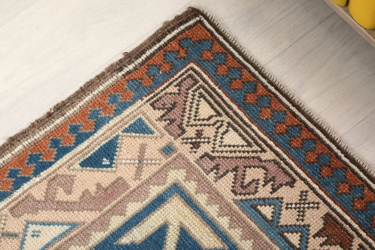 Close-up of the upper right corner of the rug, showing the rust and blue patterned border.