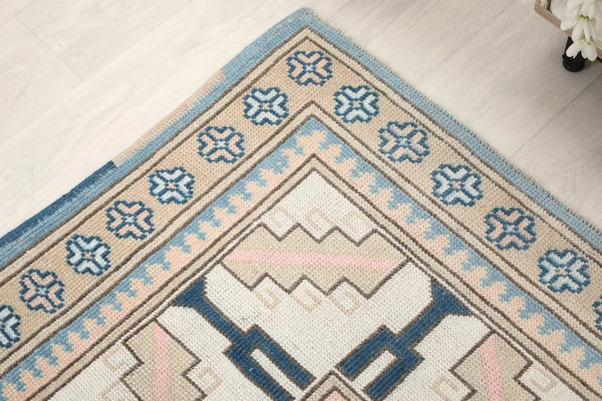 Corner detail of the rug showing the layered borders and geometric designs in blue and beige