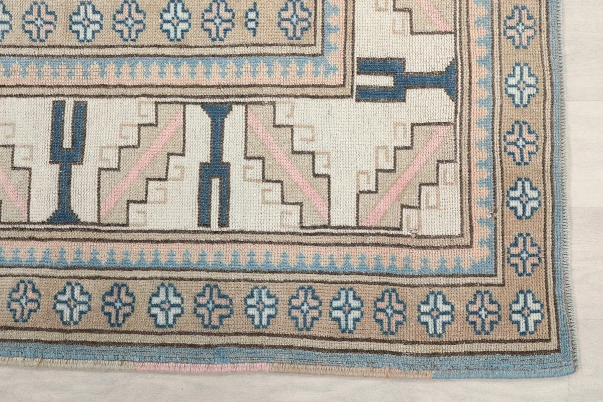 Detail of the rug's border with beige, blue, and pink geometric motifs