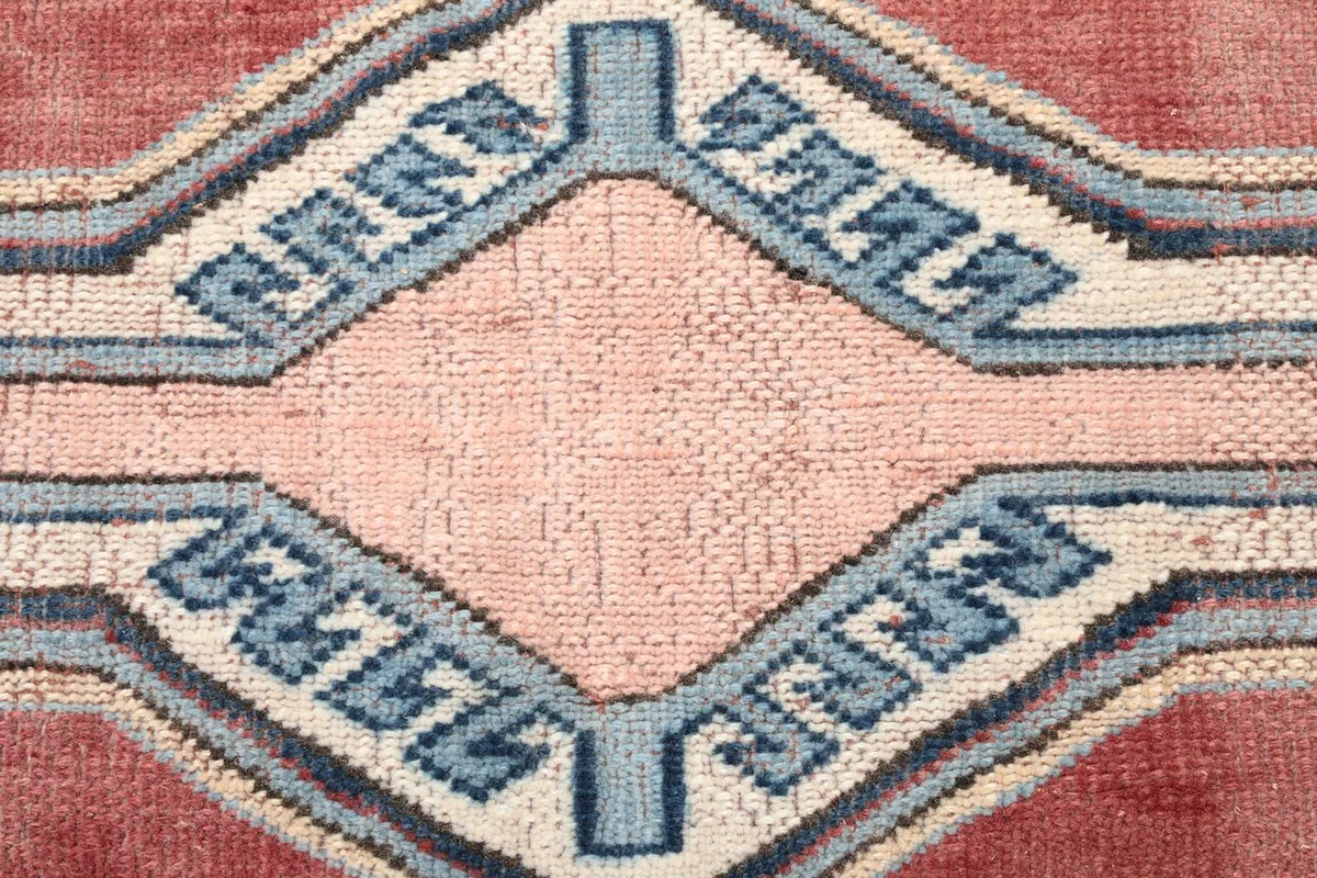 Close-up of the central medallion-like geometric motif in rust, pink, and blue