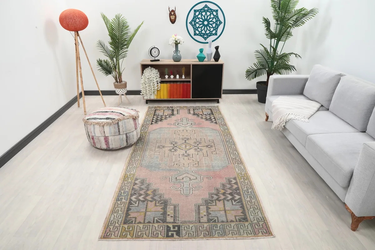 Vintage rose and blue geometric runner placed in a modern living room setting with a sofa and pouf