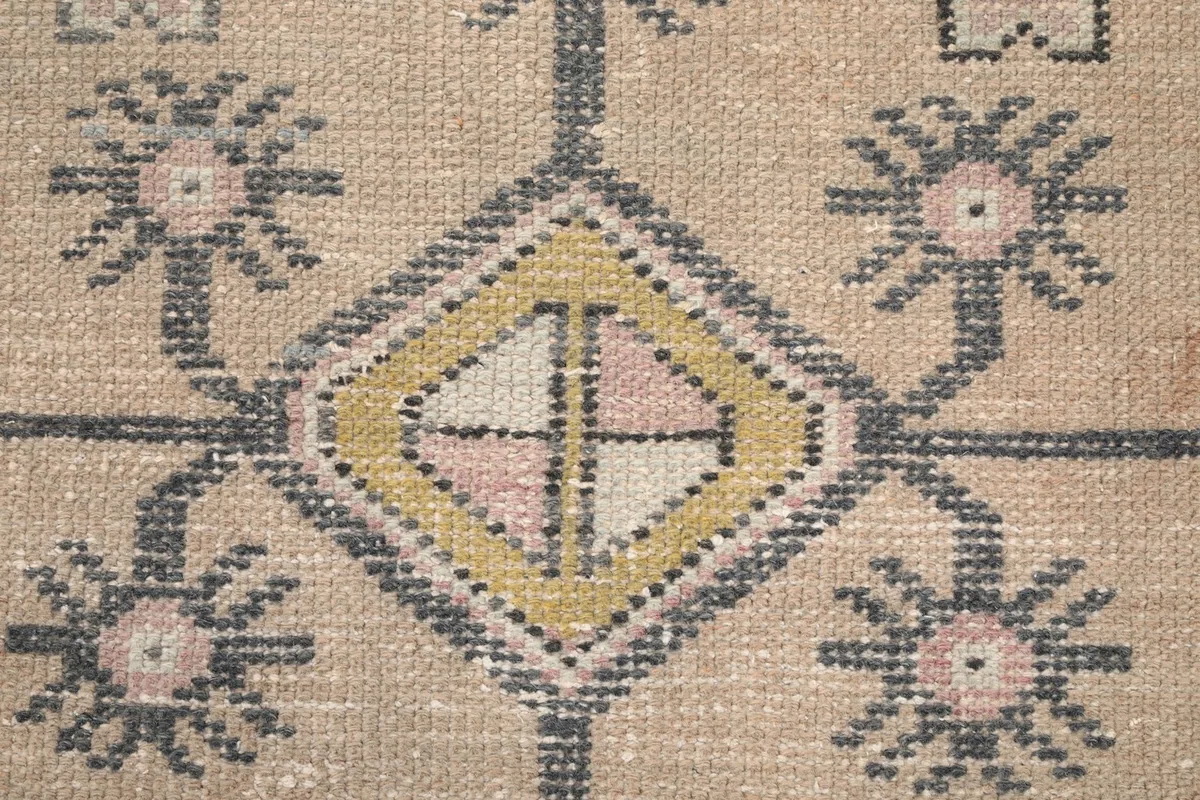 Macro detail of the central diamond motif, showcasing the hand-knotted wool pile and colors
