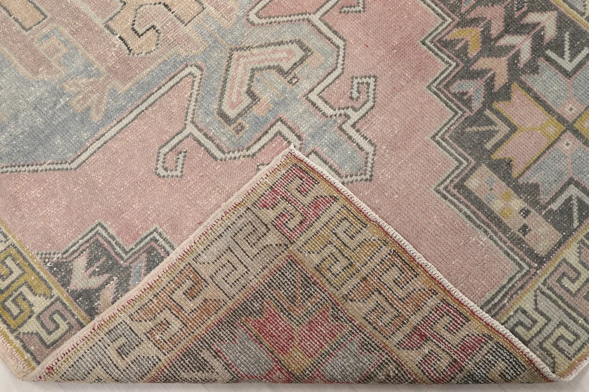 Corner folded back to reveal the cotton foundation and reverse side of the hand-knotted rug
