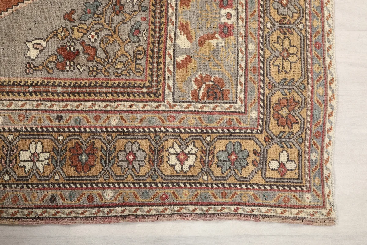 Detailed view of the rug's border design featuring small floral and geometric patterns in beige and rust