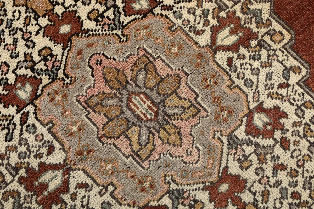 Extreme close-up of the central floral motif within the medallion, showing wool pile texture