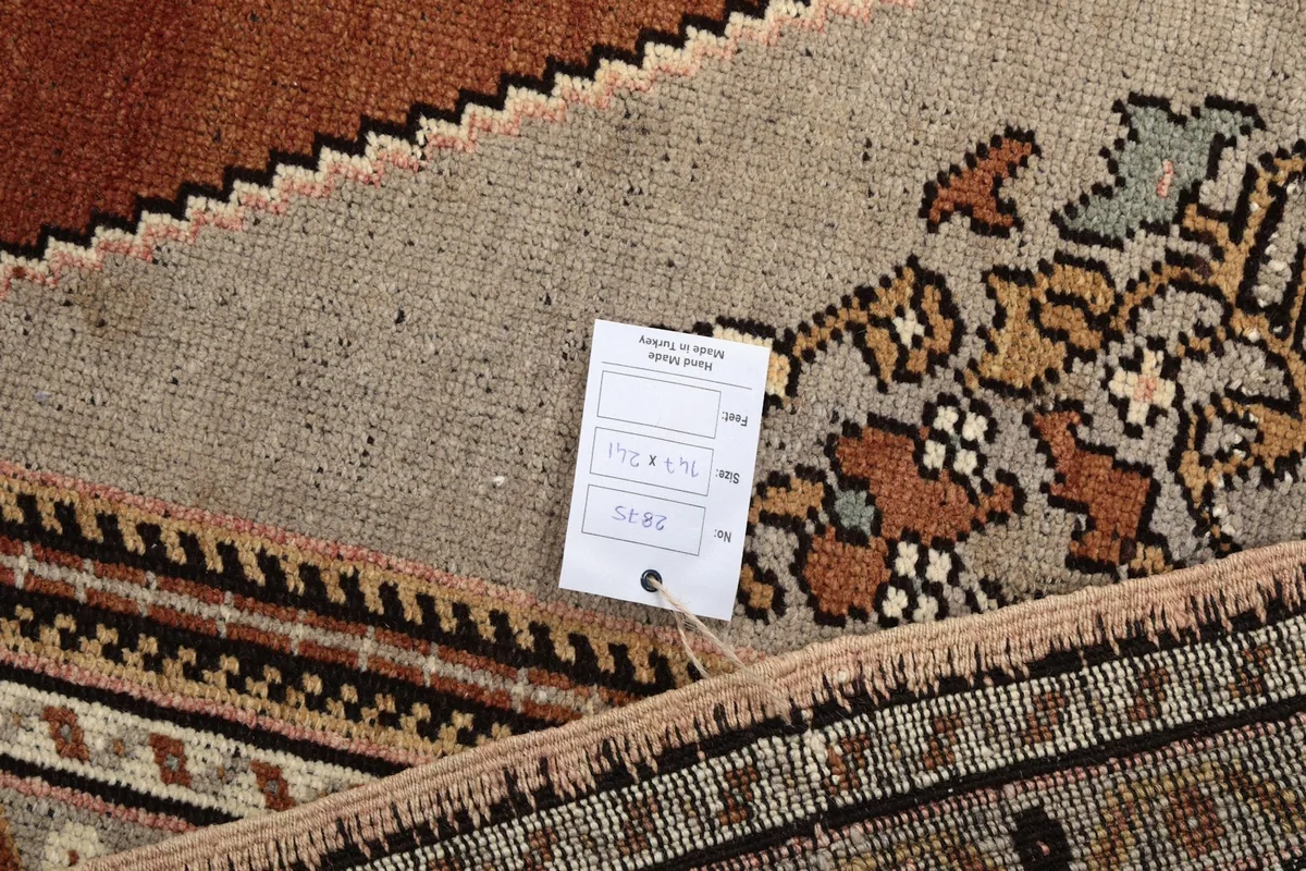 Detail of the rug's back with a tag, showing the reverse side's construction and color