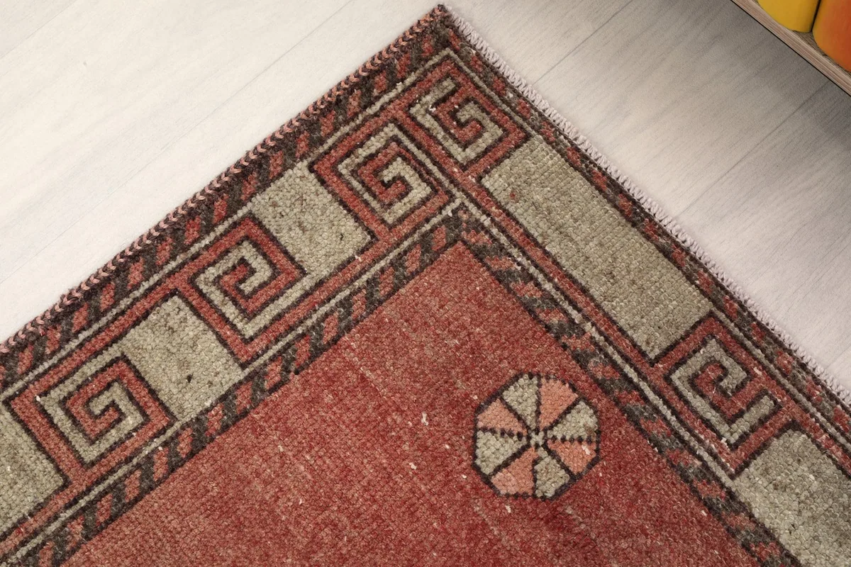 Corner detail of the rug's border, showcasing the geometric key pattern and field color.
