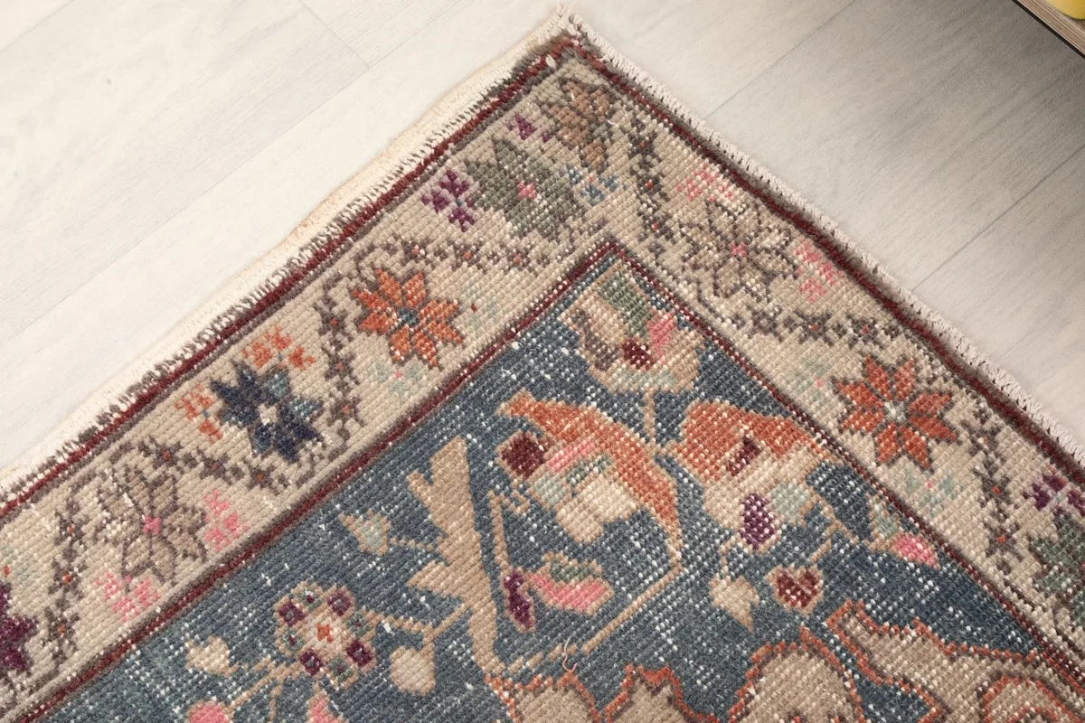 Detailed shot of the rug's outer border and corner, featuring floral and geometric motifs