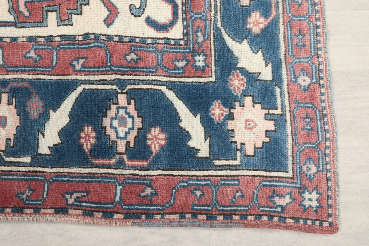 Detail of the navy and pink geometric border design on the corner of the rug
