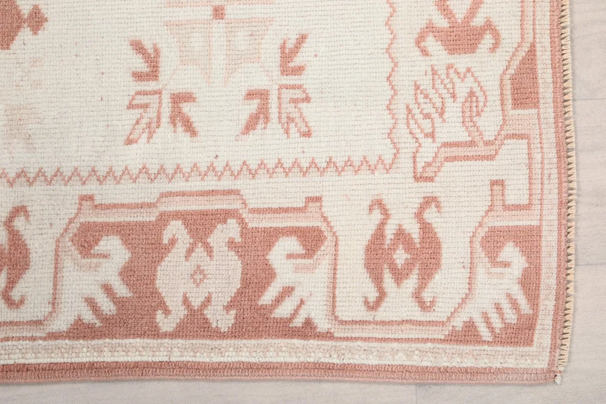 Detailed view of the rust tribal motifs and cream field on the rug's border