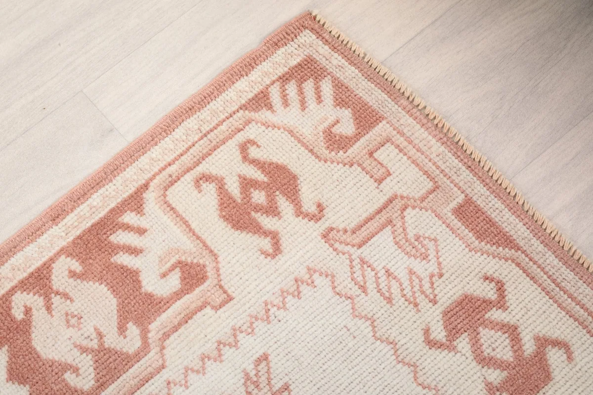 Corner detail of the rug, showing the intricate rust border and fringe