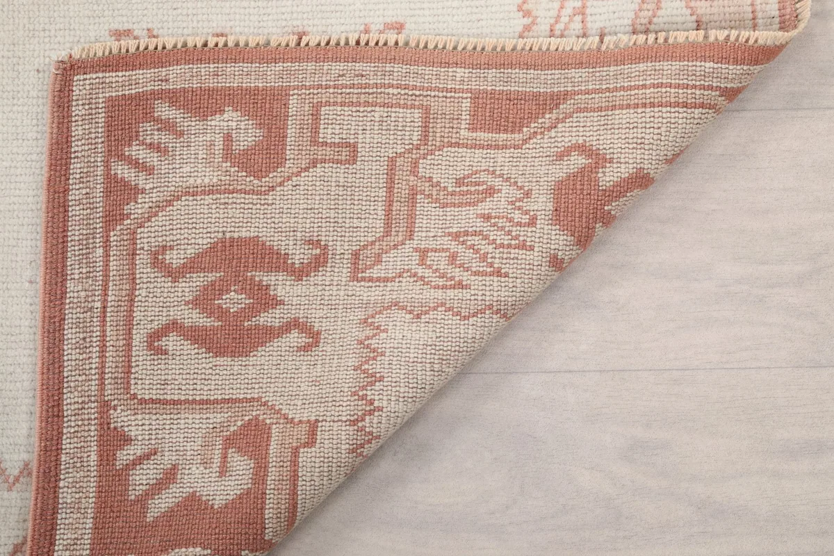View of the rug's underside and folded corner, showing hand-knotted construction