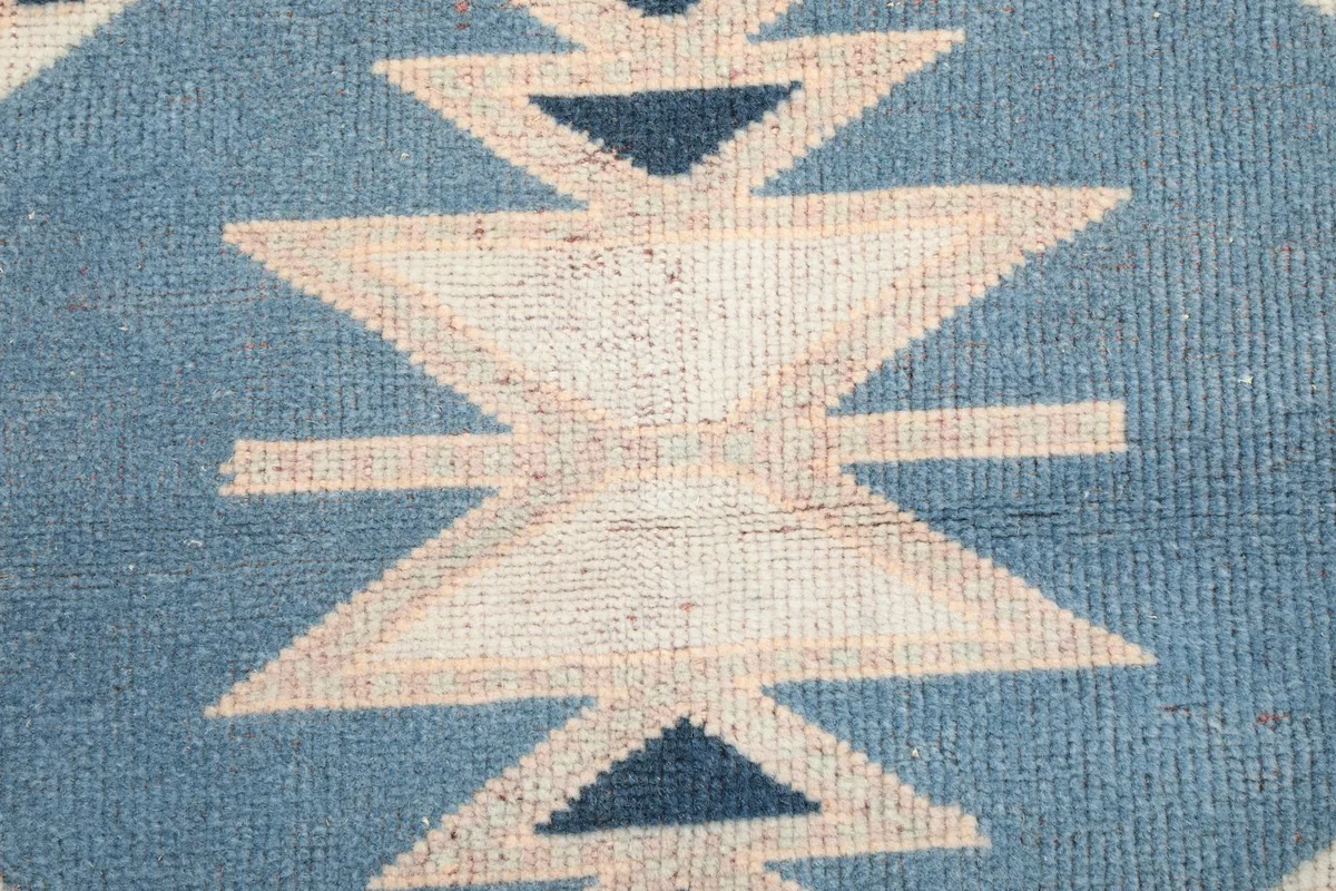 Texture and low pile of the rug, showing the central blue and cream design