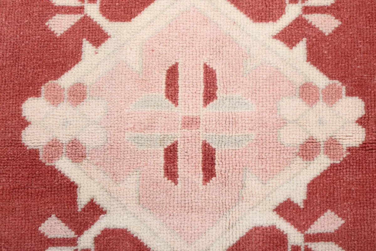 Close-up of a central medallion motif with varying shades of rose and cream wool pile.
