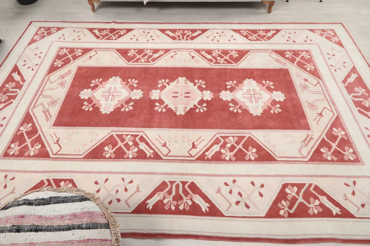 Full overhead view of the rose and cream vintage rug, showing all patterns and field.