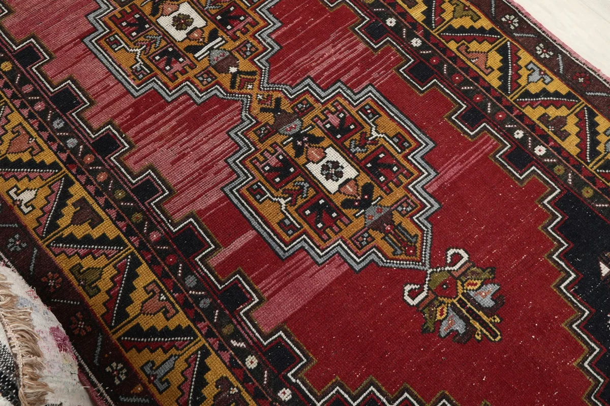 Close-up of the central red field and geometric medallion, showing color variations in the wool pile.