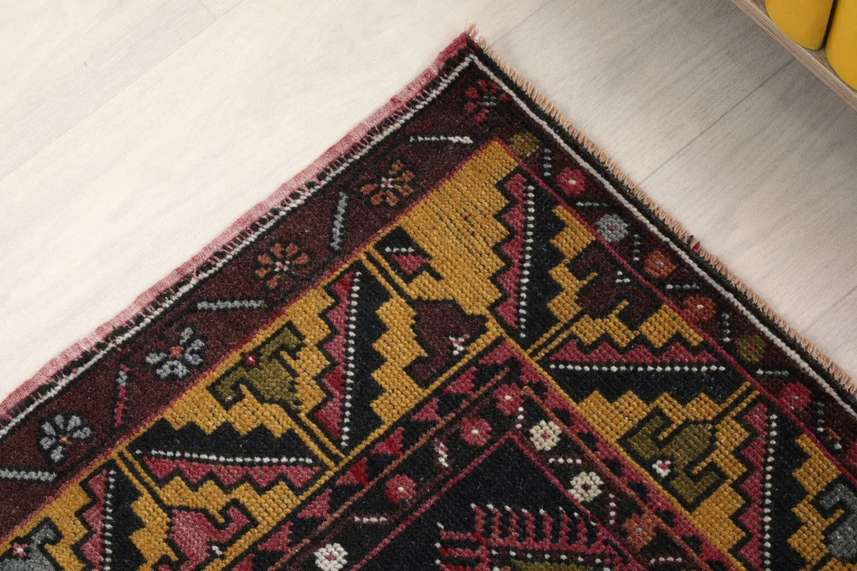 Close-up of the rug's border and corner, detailing the tribal geometric motifs in gold, black, and red.