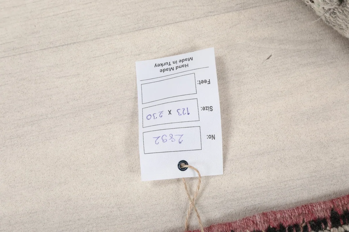 Tag attached to the rug, displaying its dimensions in centimeters and country of origin.