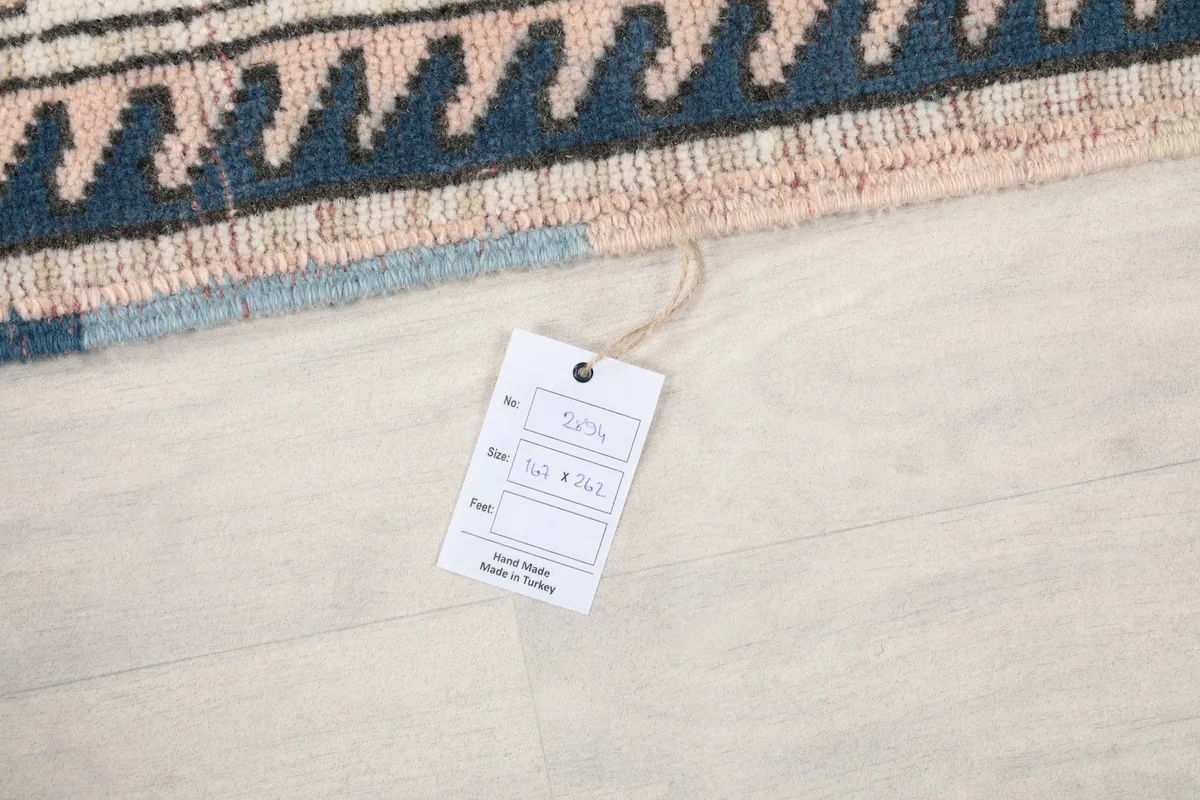Rug tag displaying the size 5'6" x 8'7" and hand-knotted origin