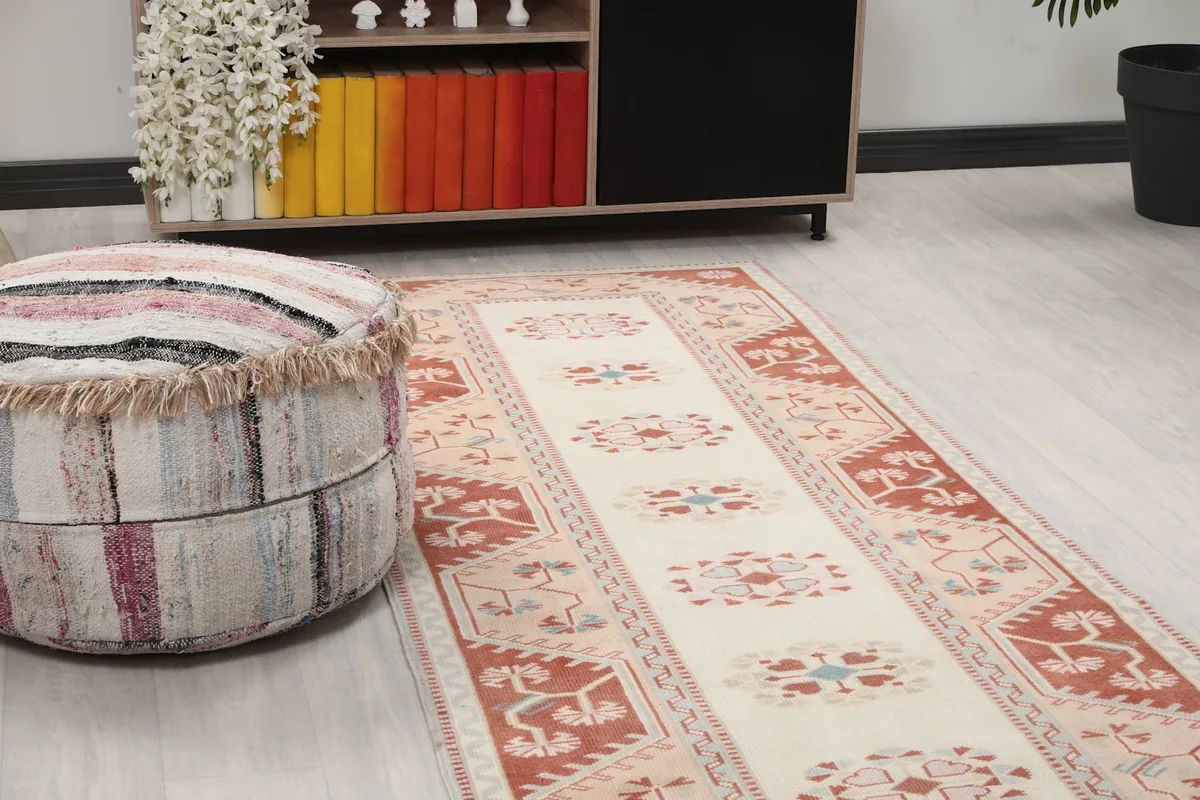 Close-up of the runner rug showing its geometric motifs and colors next to a striped pouf