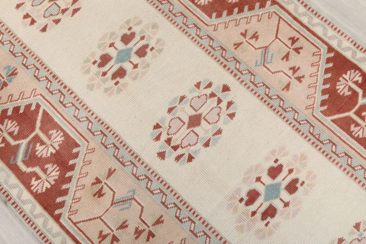 Overhead view of the ivory field with geometric medallions in rust, pink, and blue