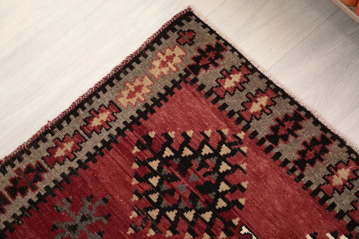 Close-up of the rug's border design and the transition to the main red field