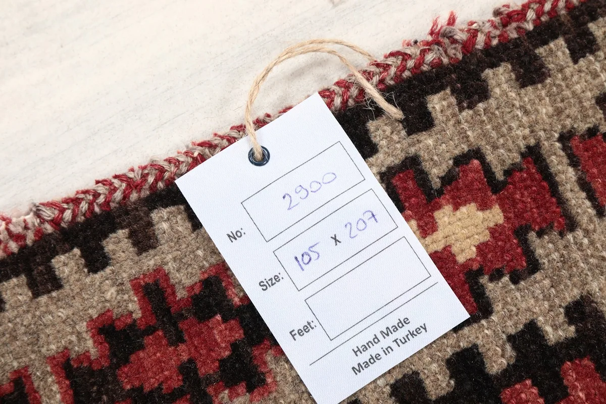 Close-up of the rug's edge with a product tag showing measurements in cm