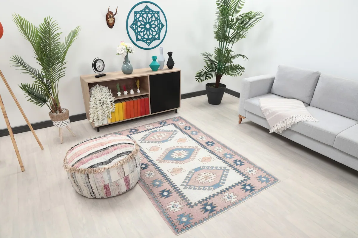 Overhead view of the rose and ivory rug placed in a living space with a sofa and pouf