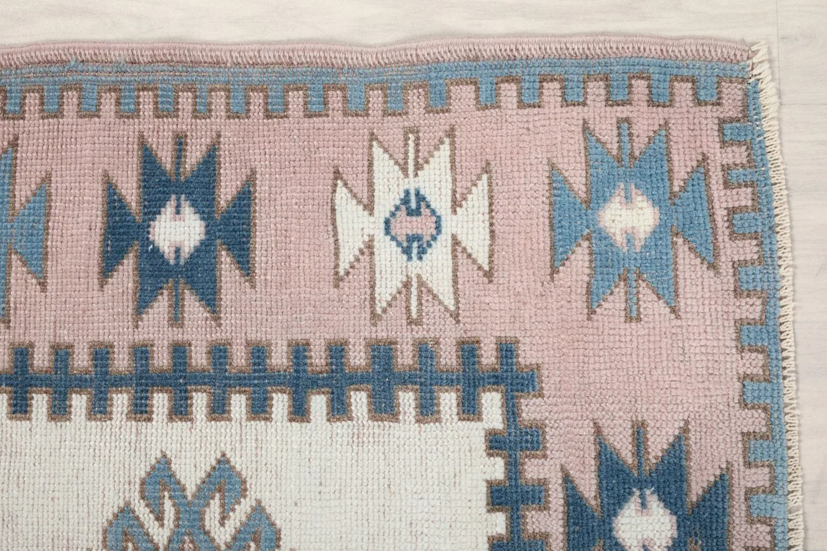 Detail of the rose border and blue tribal motifs on the vintage wool rug