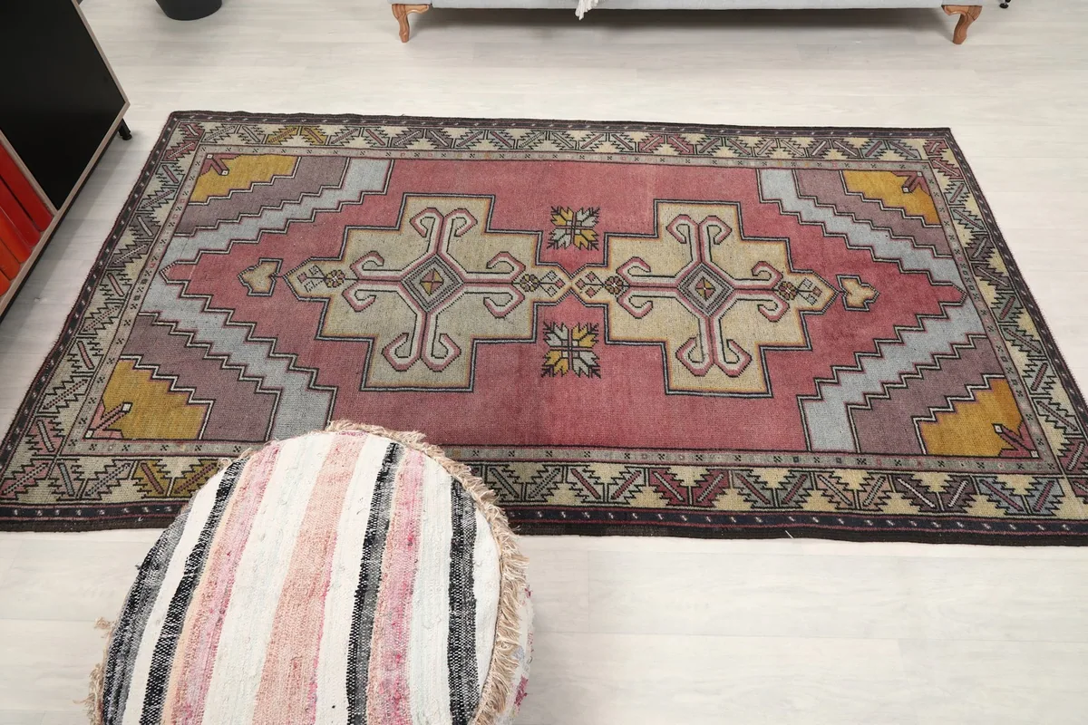 Full view of the rug on a light floor, with an ottoman in the foreground