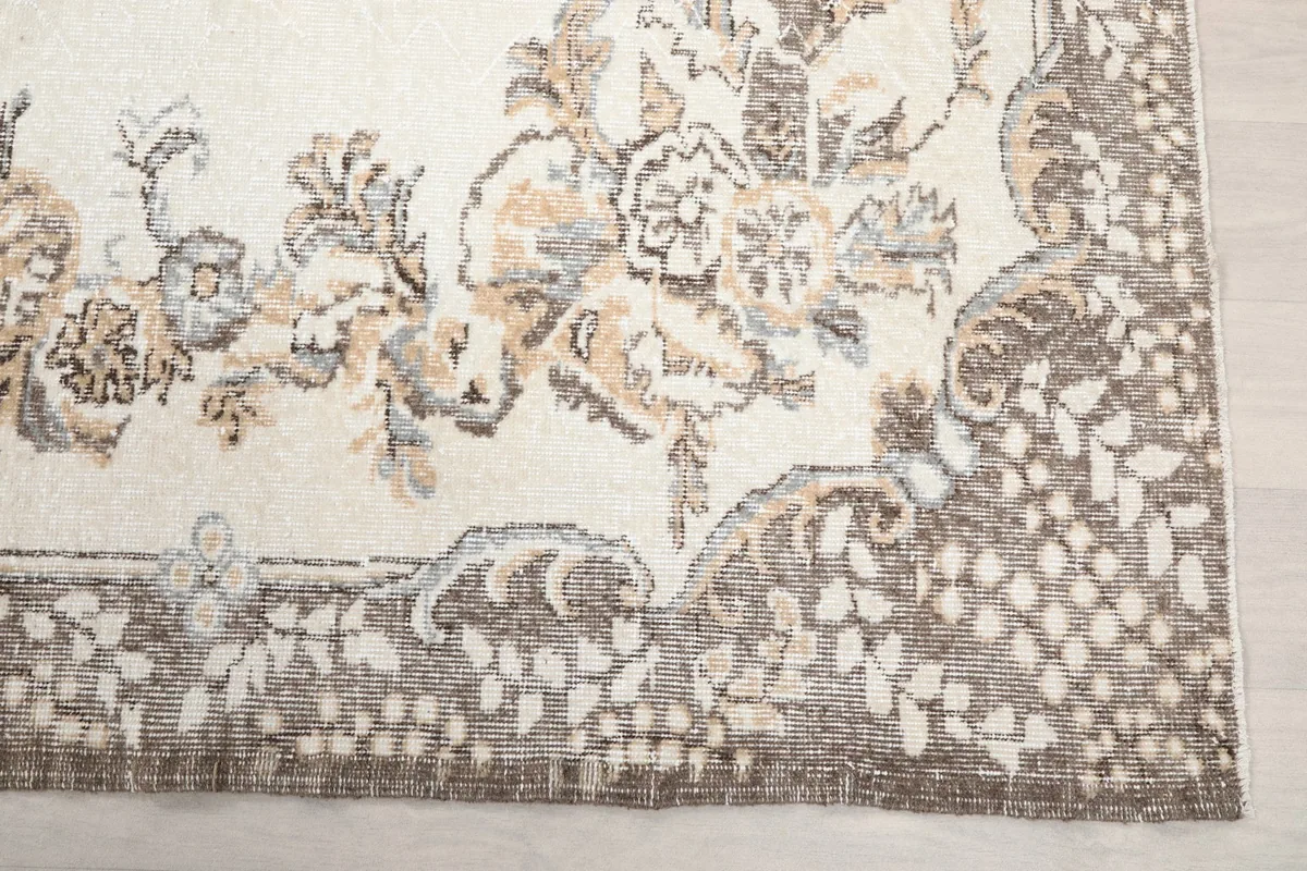 Detailed view of the corner border and floral motifs on the ivory rug