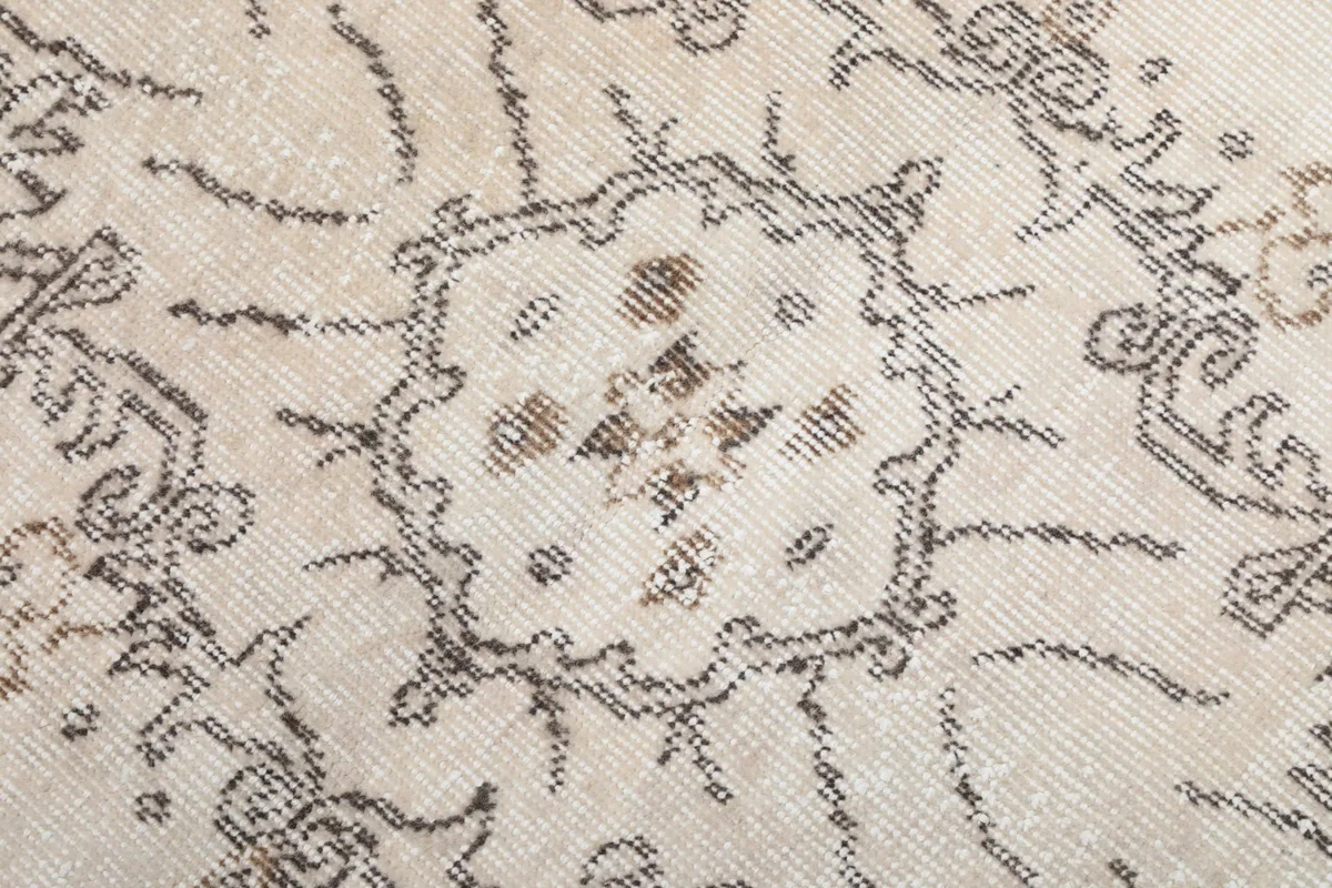 Extreme close-up showing the low pile texture and intricate hand-knotted details of the rug