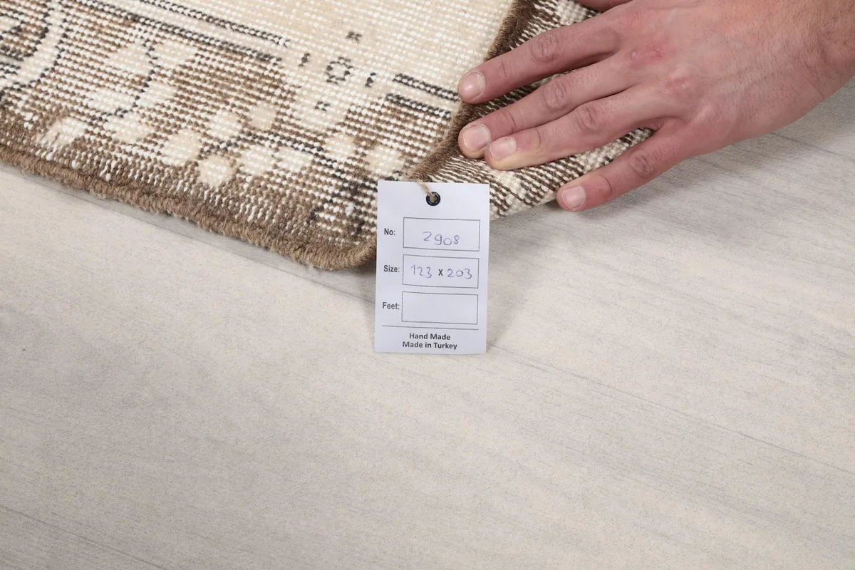 Hand holding a tag with product information next to the folded edge of the rug