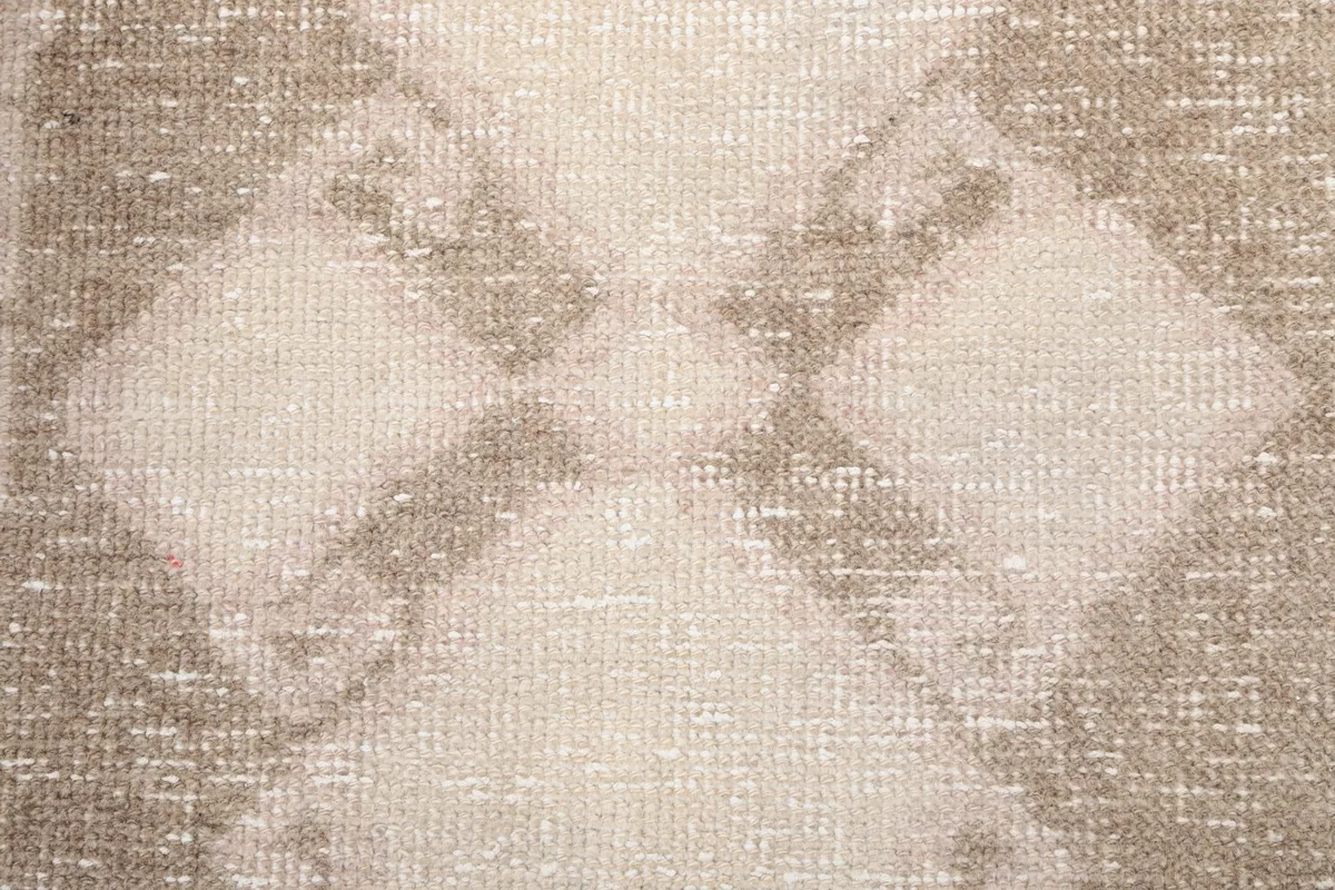 Texture detail of the rug's low wool pile and distressed surface