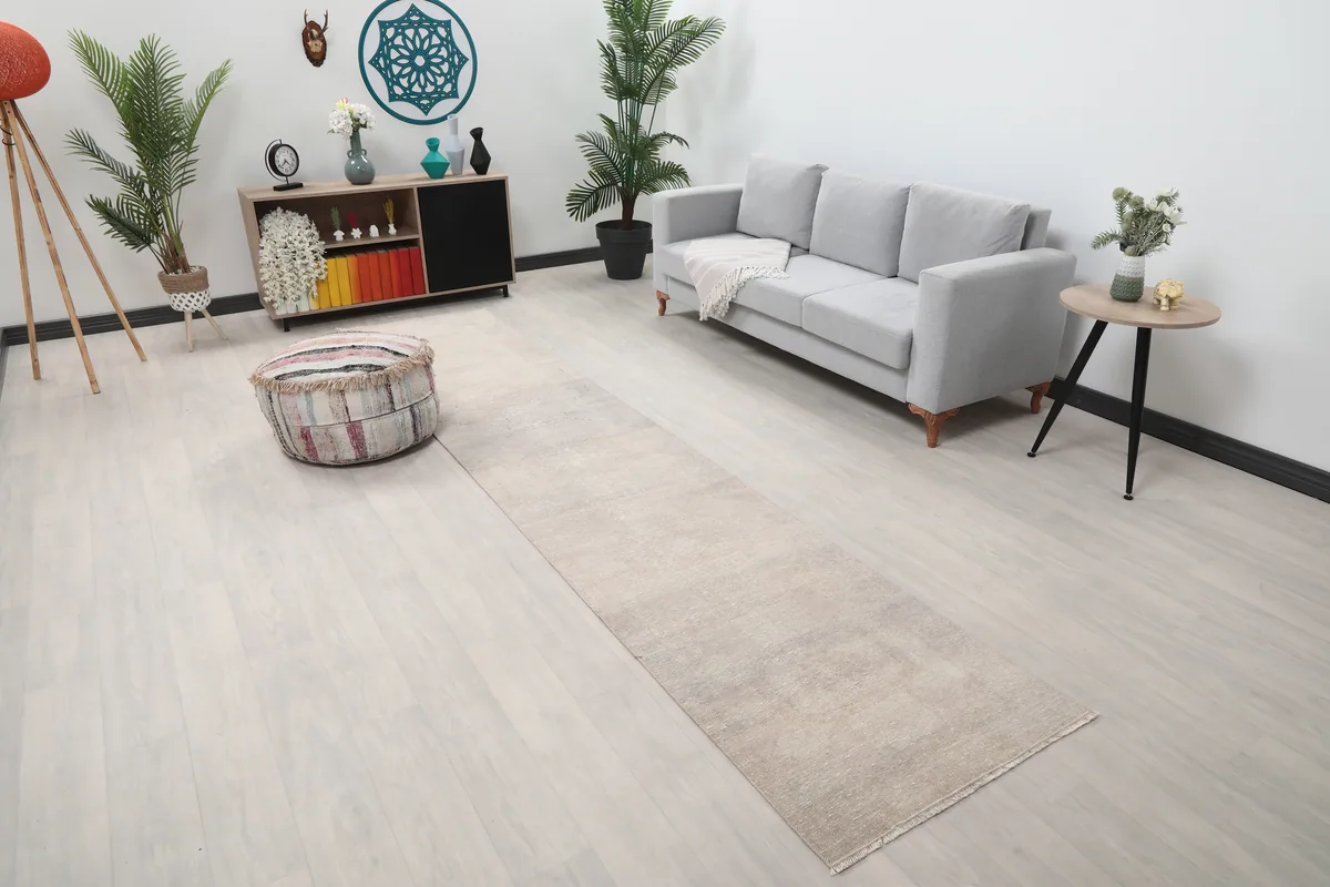 Beige Distressed Anatolian Runner placed in a room, showing its length next to a sofa and ottoman.