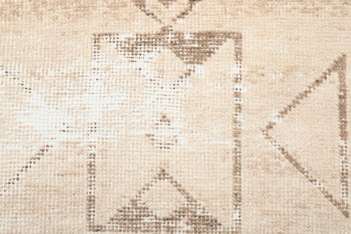 Extreme close-up showing the hand-knotted texture and faded tan tribal design elements