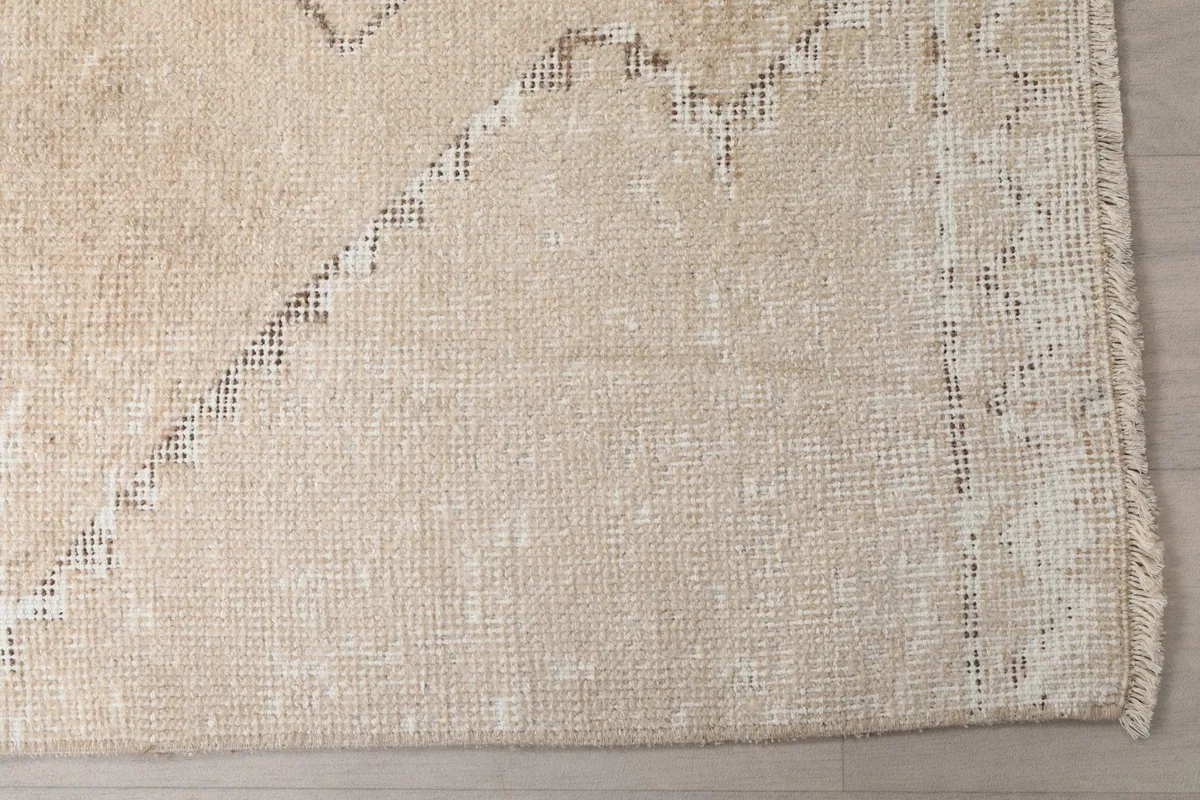 Detailed view of the low wool pile and cotton foundation visible through areas of wear on the runner