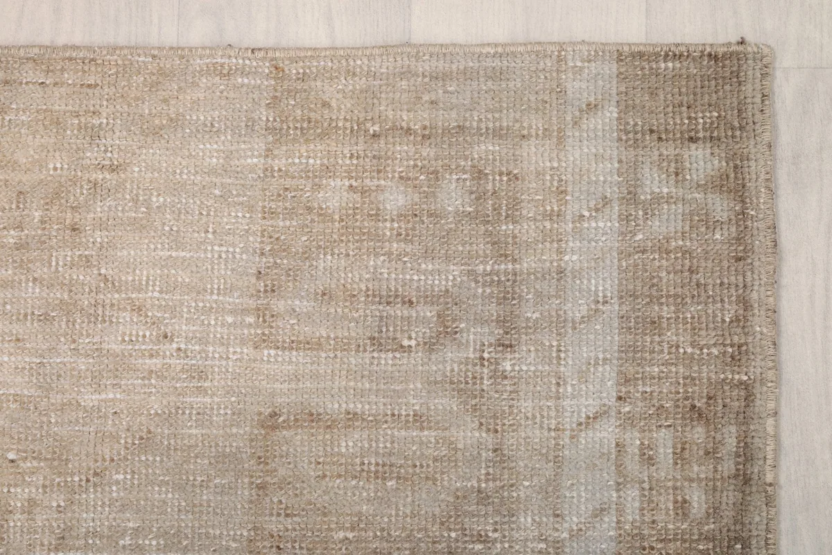 Detailed view of the rug's corner showcasing the subtle geometric pattern and muted colors